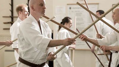 People practicing with wooden staff weapons at our Brighton classes for adults